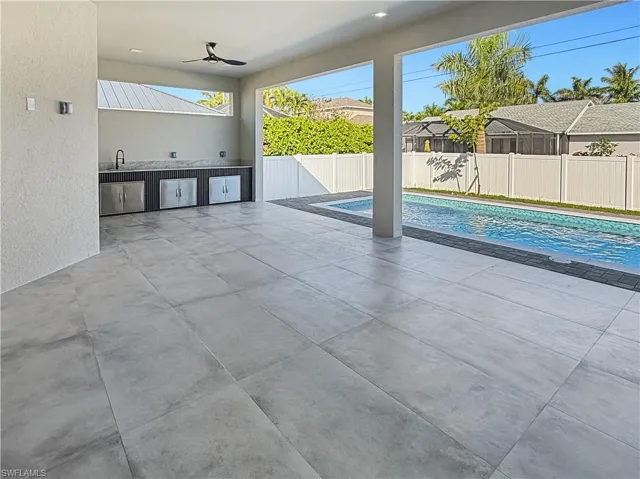 View of swimming pool featuring an outdoor kitchen, a patio area, ceiling fan, and a fenced backyard