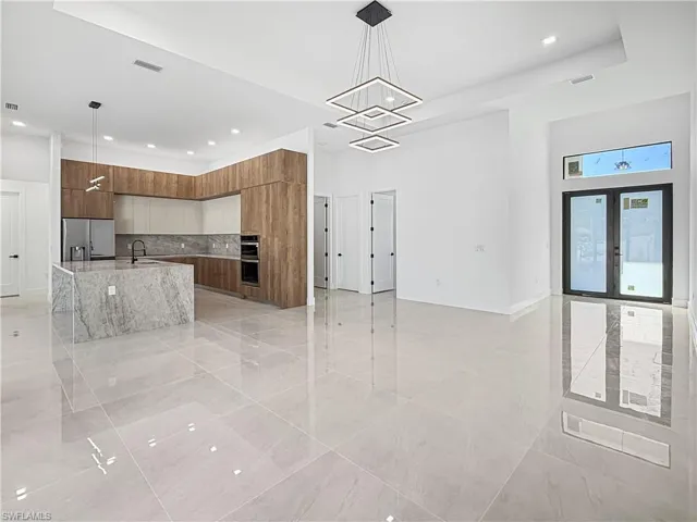 Kitchen with modern cabinets, decorative light fixtures, open floor plan, brown cabinets, and decorative backsplash