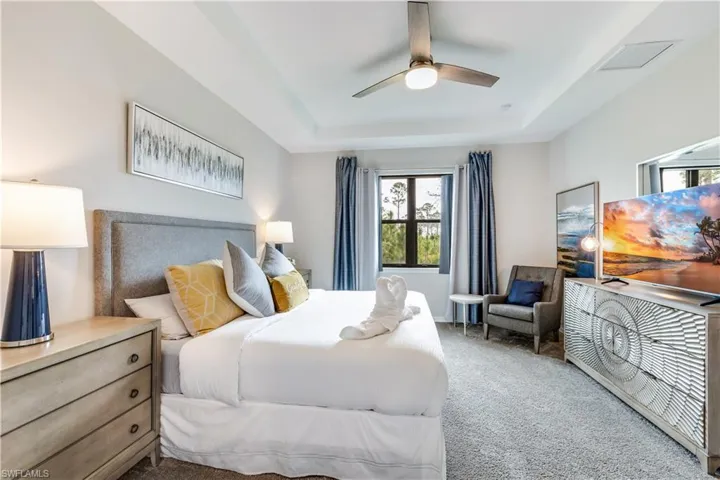 Carpeted bedroom with ceiling fan and a raised ceiling