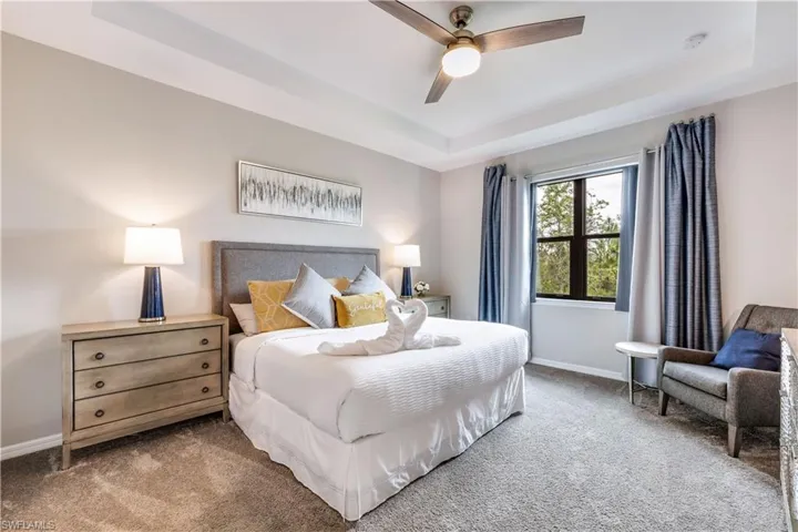 Bedroom with carpet, ceiling fan, and a raised ceiling