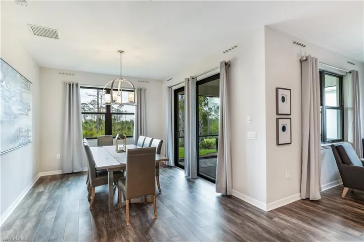 Dining area with a notable chandelier, plenty of natural light, and dark wood-type flooring