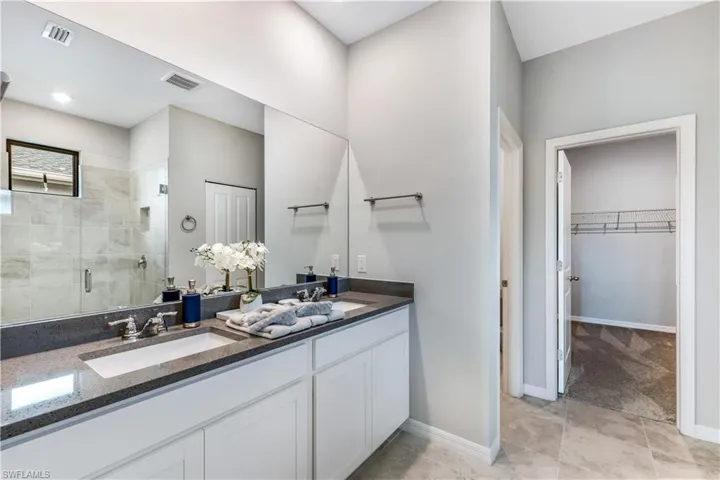 Bathroom featuring dual vanity, tile patterned floors, and walk in shower