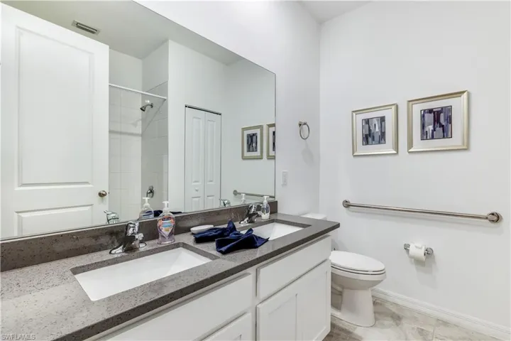 Bathroom with tile patterned flooring, toilet, and dual bowl vanity