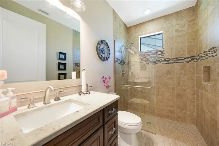 Bathroom with vanity, tiled shower, and toilet