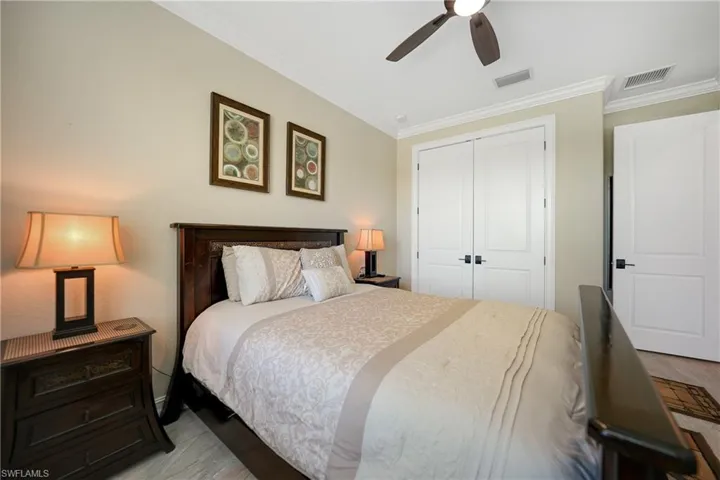 Bedroom with crown molding, light hardwood / wood-style floors, a closet, and ceiling fan