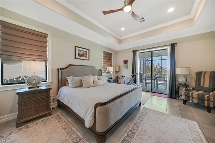 Bedroom featuring access to exterior, light tile patterned floors, crown molding, a raised ceiling, and ceiling fan