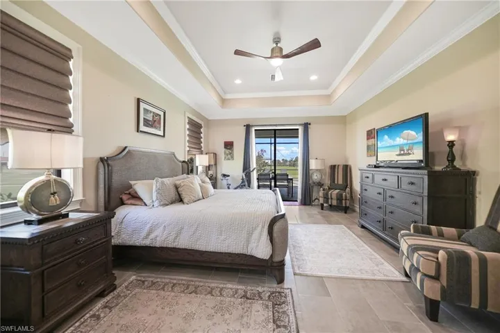 Bedroom featuring access to outside, a tray ceiling, crown molding, and ceiling fan