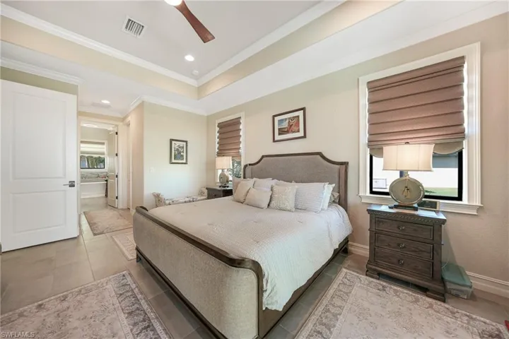 Bedroom with crown molding, ensuite bathroom, tile patterned flooring, and ceiling fan