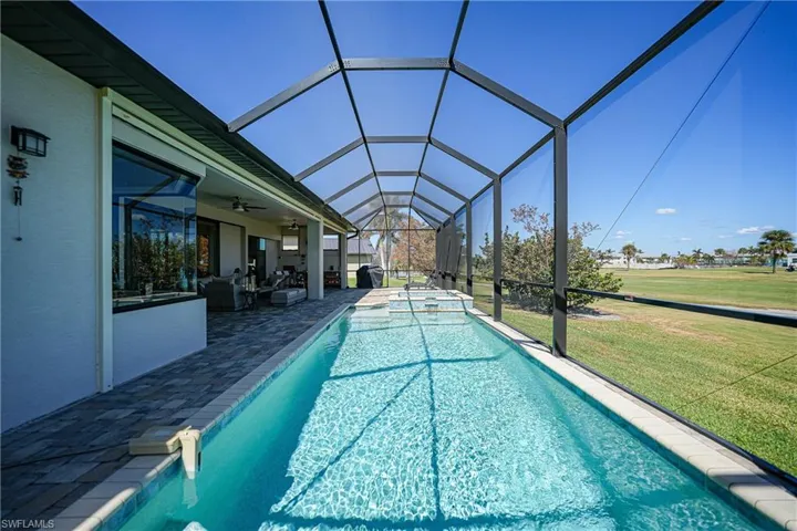 View of swimming pool with a patio area, glass enclosure, a yard, an outdoor hangout area, and ceiling fan