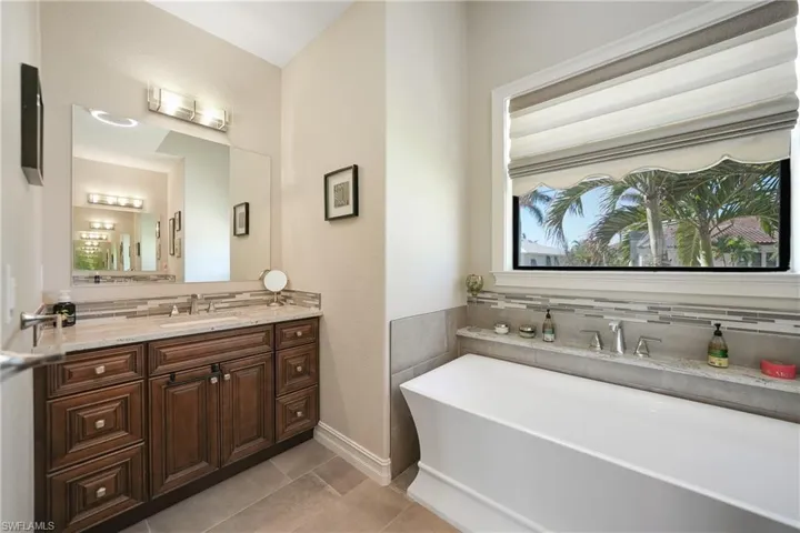 Bathroom featuring vanity, decorative backsplash, tile patterned floors, and a washtub