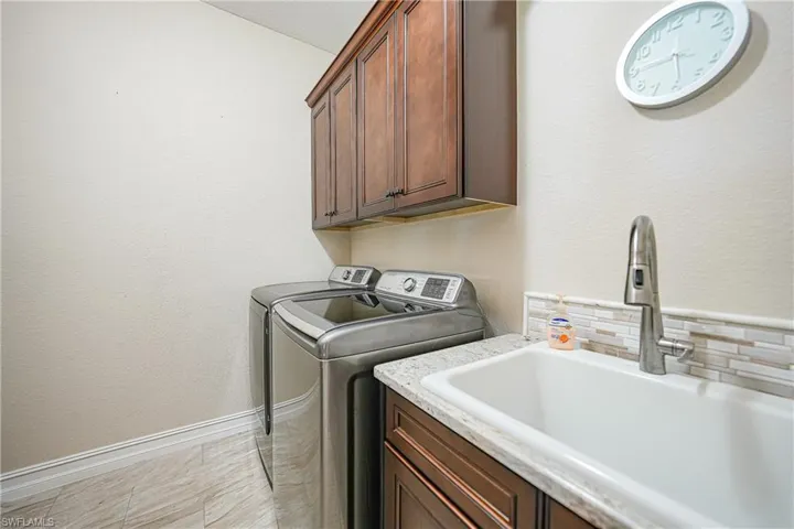 Laundry room featuring cabinets, washer and dryer, sink, and light tile patterned floors