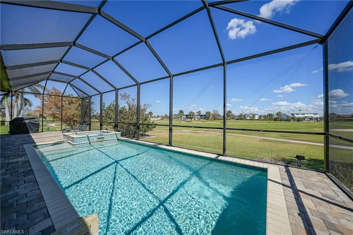 View of pool with a lawn, a patio, and glass enclosure