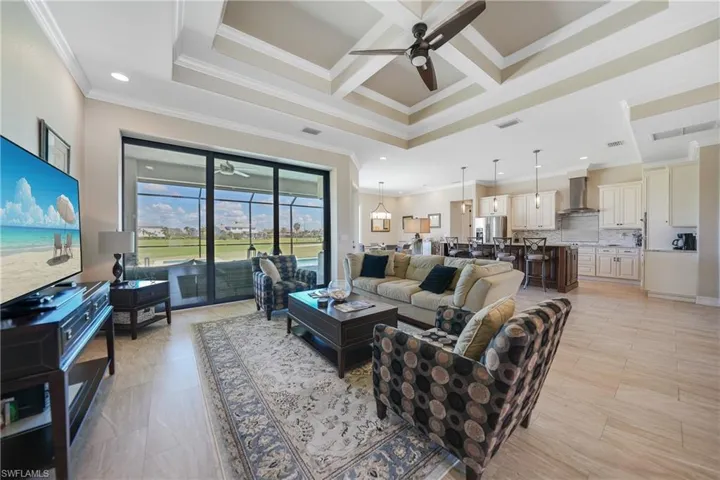 Living room featuring beam ceiling, coffered ceiling, crown molding, and ceiling fan