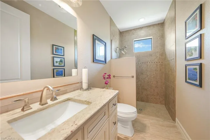 Bathroom with toilet, vanity, and tiled shower