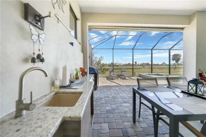 View of patio with area for grilling, a lanai, and sink