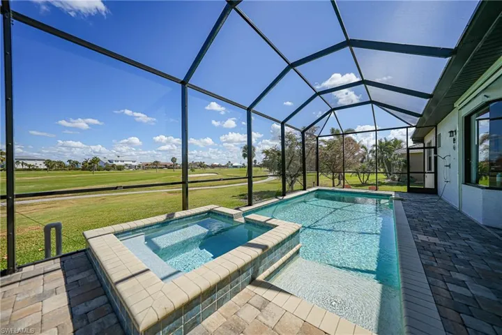 View of swimming pool with a patio, an in ground hot tub, a lawn, and a lanai