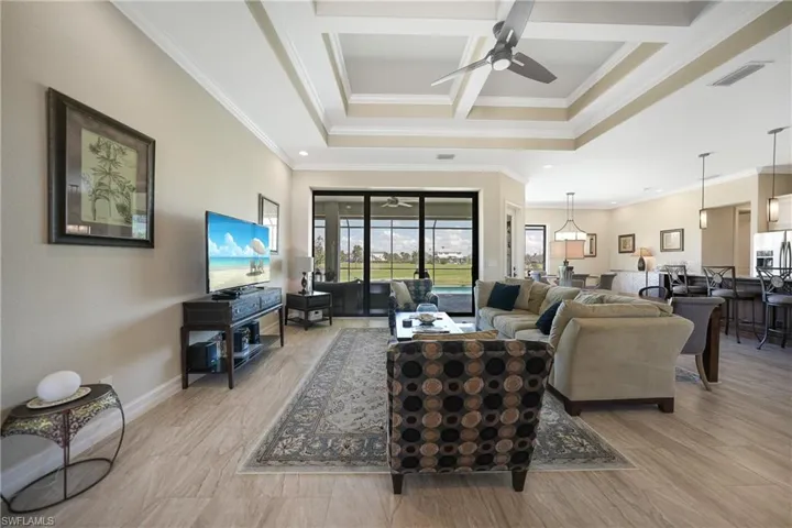 Living room with light wood-type flooring, ceiling fan, coffered ceiling, beamed ceiling, and crown molding