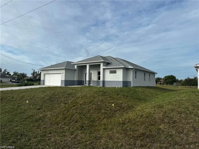 View of front of property featuring a garage and a front yard