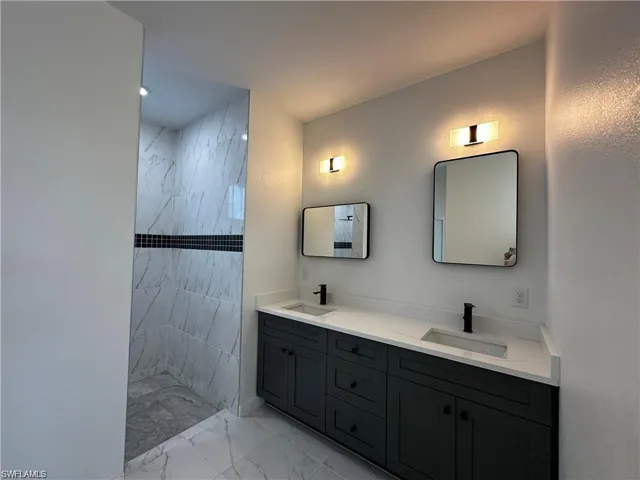 Bathroom featuring tiled shower and vanity
