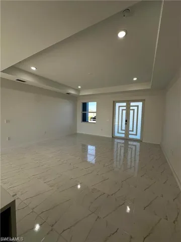 Unfurnished living room with a raised ceiling and french doors