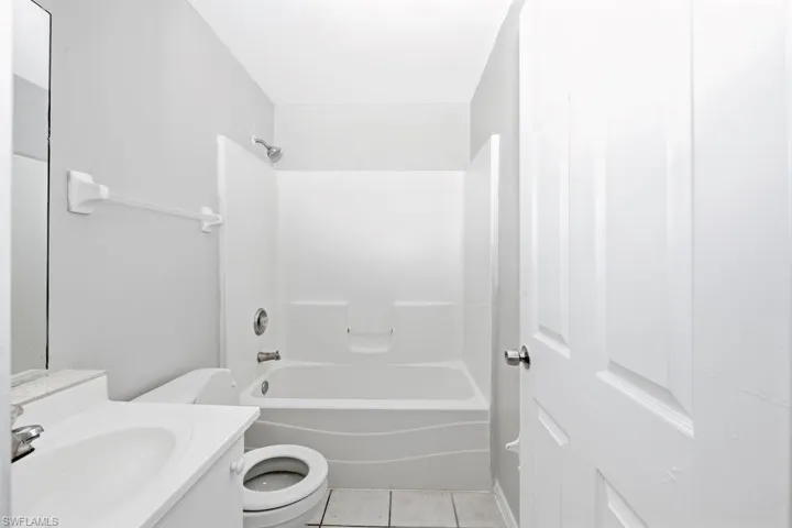 Bathroom featuring a white bathtub, integrated shower, and white vanity with an undermount sink