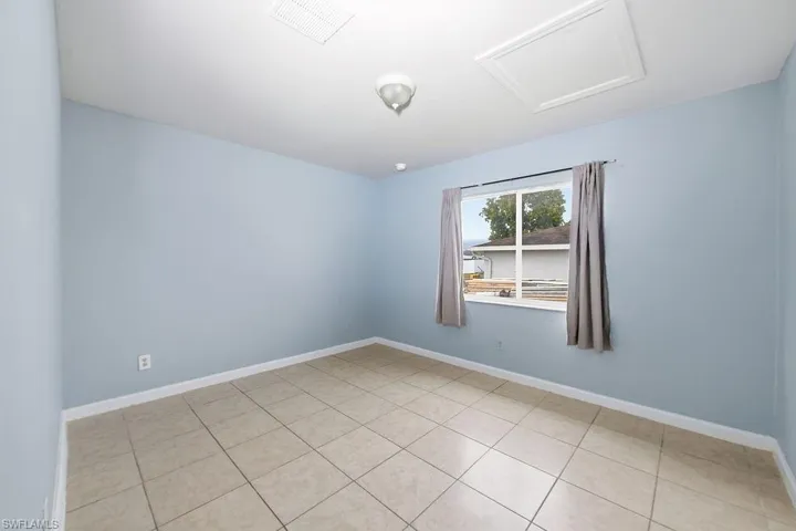 Room with light blue walls, ceramic tile flooring, and white baseboards
