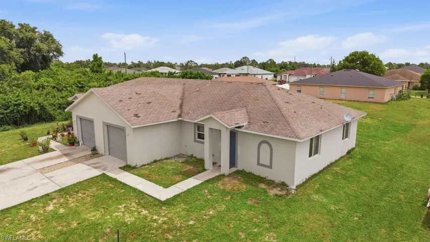 Light-toned stucco exterior with a brown shingle roof