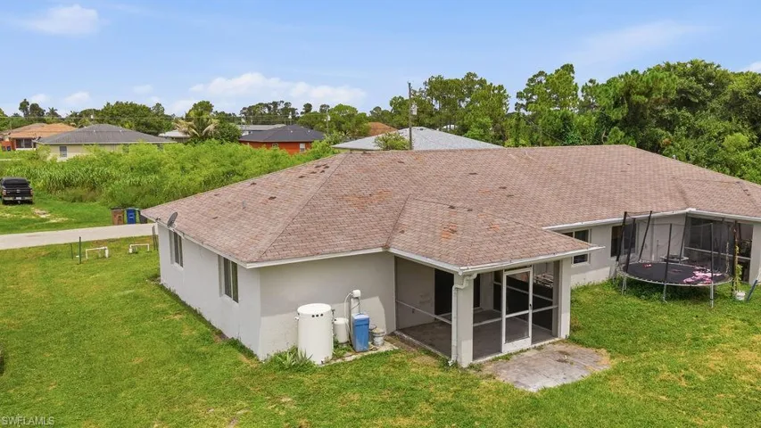 Expansive rear exterior with a screened lanai, mature landscaping, and a substantial shingle roof