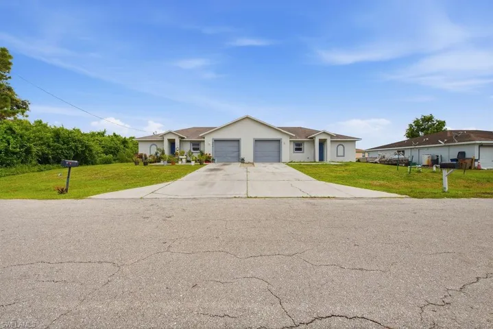 Duplex property featuring a neutral exterior, individual garage doors, and separate entryways