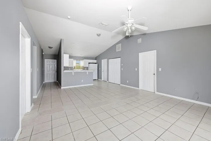 Open-concept living space featuring vaulted ceilings, tile flooring, and a ceiling fan