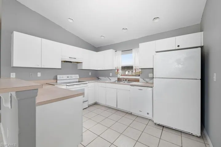 Kitchen featuring white cabinetry, light countertops, white appliances, and tiled flooring