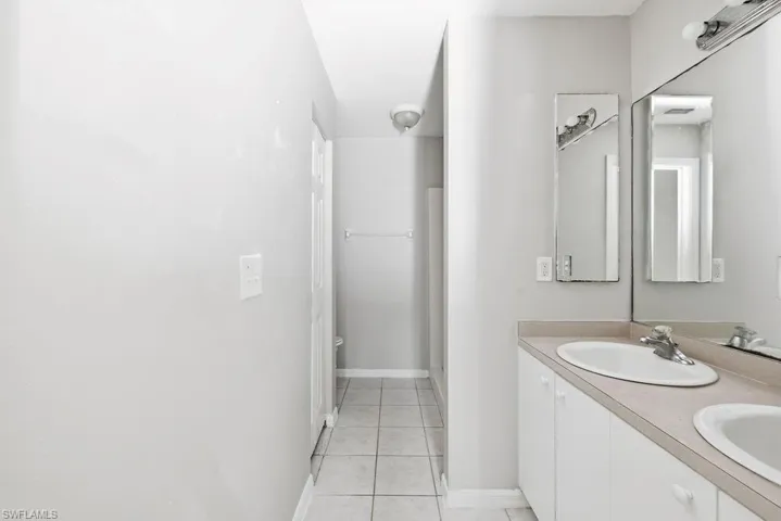 Dual vanity with integrated sinks, chrome faucets, expansive wall mirror, and lower cabinetry