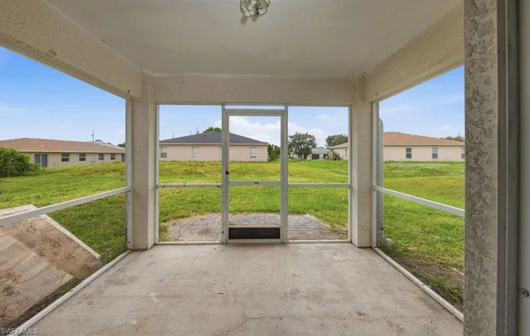 Screened patio featuring a concrete floor and a screened door opening to a grass yard