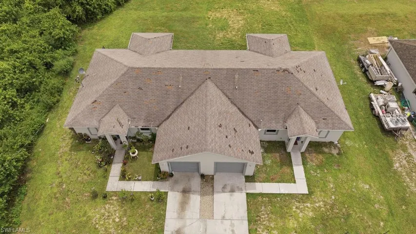 Duplex property featuring a shingle roof, light-colored exterior siding, and individual attached garages
