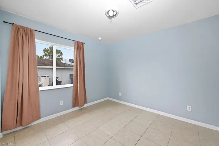 Room with light blue painted walls, neutral tile flooring, and a window with a white frame