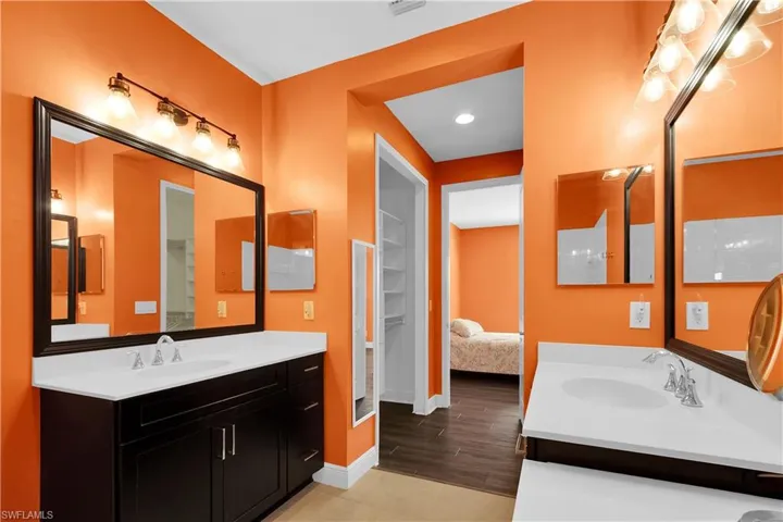 Ensuite bathroom featuring two vanities, light wood finished floors, and recessed lighting