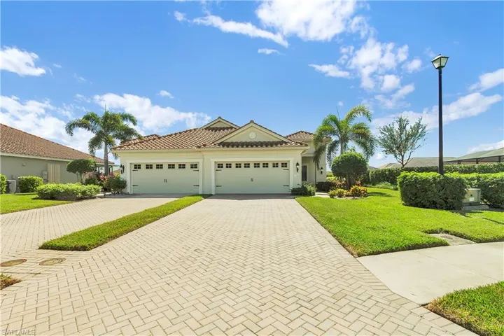 Mediterranean / spanish home with decorative driveway, a front yard, an attached garage, a tile roof, and stucco siding