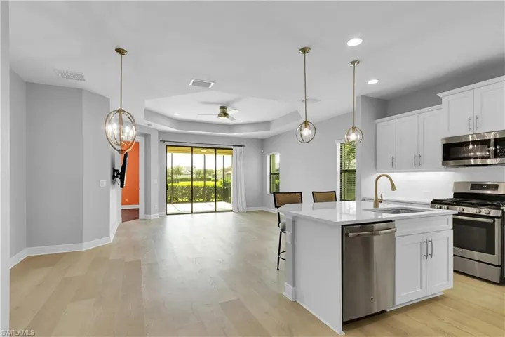 Kitchen featuring decorative light fixtures, a chandelier, appliances with stainless steel finishes, white cabinets, and open floor plan