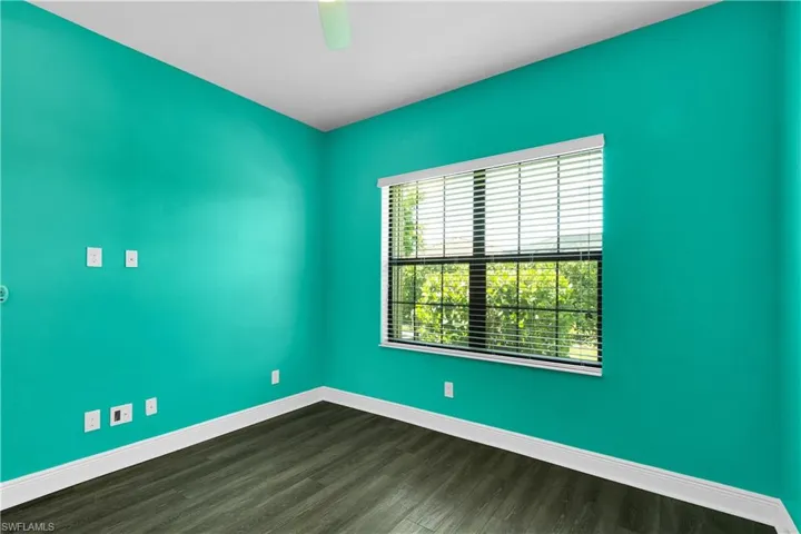 Empty room with baseboards and dark wood-type flooring