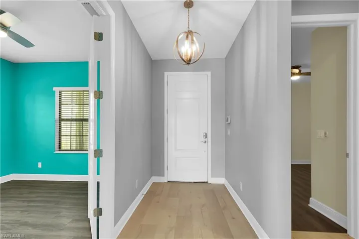 Foyer entrance with ceiling fan, wood finished floors, and a chandelier