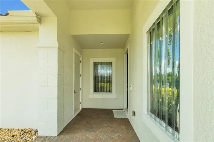 View of exterior entry featuring stucco siding and a patio
