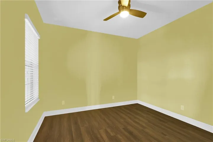 Unfurnished room featuring dark wood-type flooring and ceiling fan