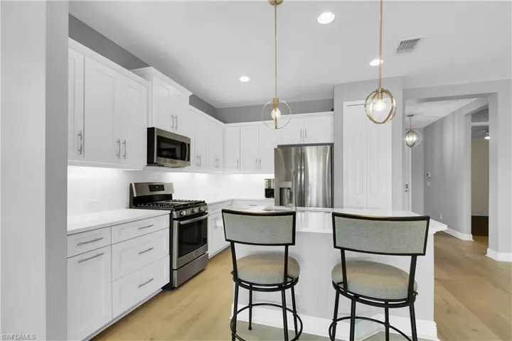 Kitchen featuring stainless steel appliances, a breakfast bar area, a center island, white cabinetry, and light wood-type flooring