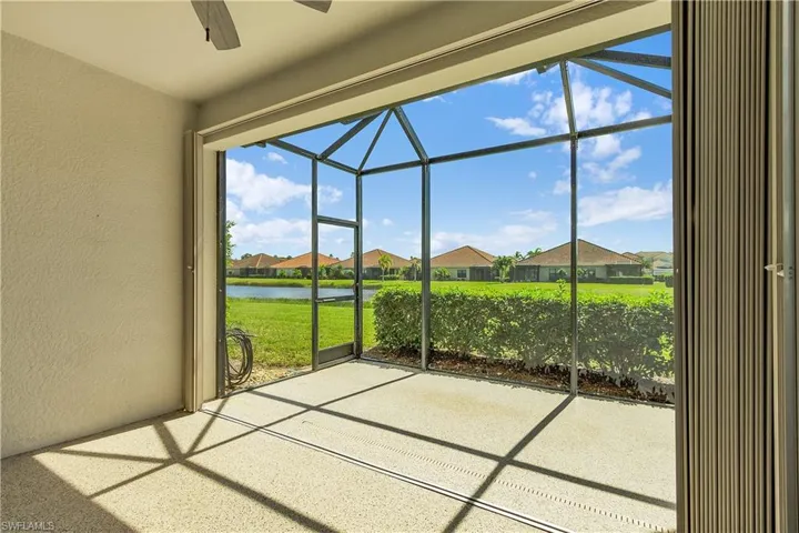 Unfurnished sunroom featuring a water view, ceiling fan, a residential view, and a patio