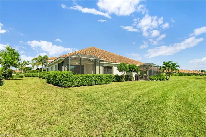 Back of house with a yard, a sunroom, glass enclosure, stucco siding, and a tiled roof