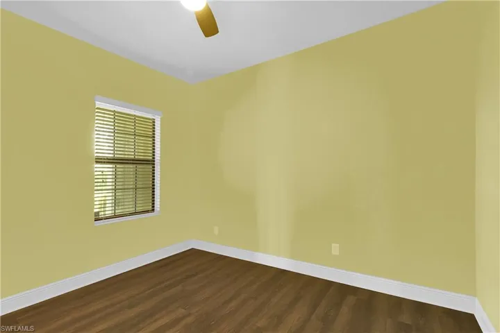 Unfurnished room featuring dark wood-style floors and a ceiling fan