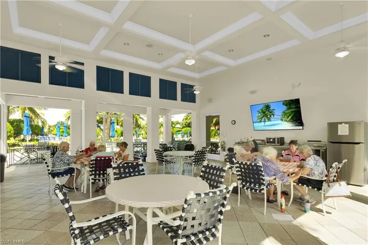 Tiled dining area with a high ceiling, a ceiling fan, and beam ceiling
