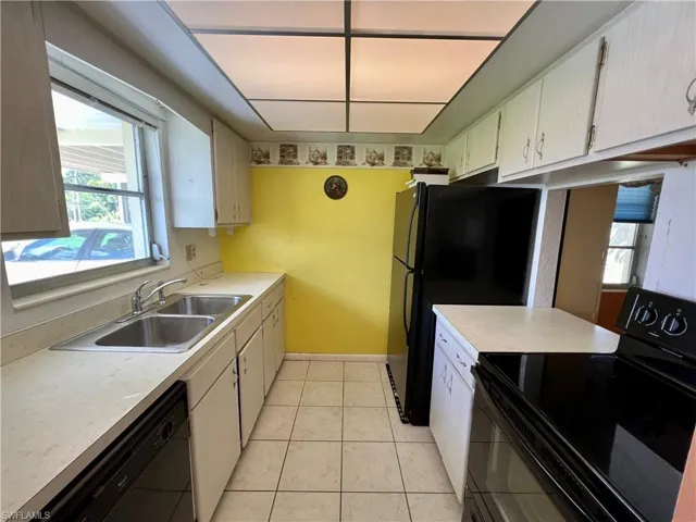 Kitchen with black appliances, sink, and light tile floors