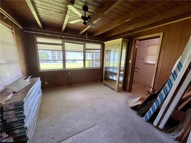 Family room featuring ceiling fan, beamed ceiling, carpet, wood walls, and wooden ceiling