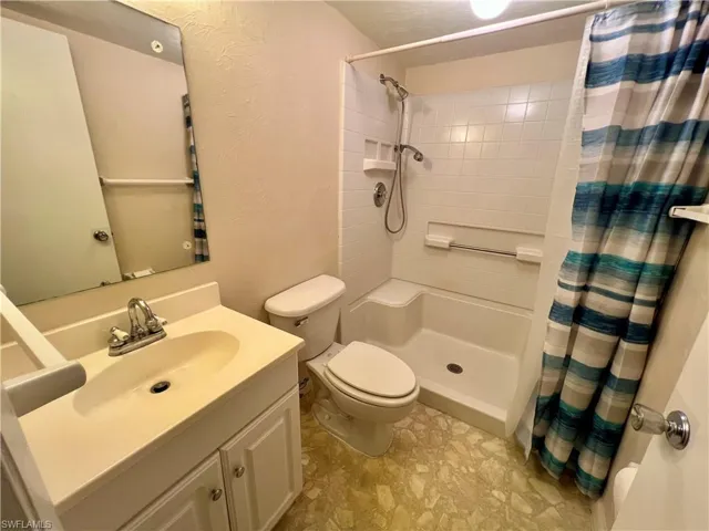 Bathroom featuring curtained shower, tile flooring, toilet, and vanity